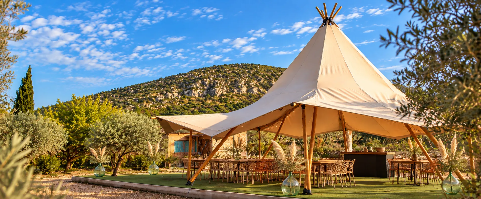 Carpa tipi blanca entre olivos con la montaña al fondo